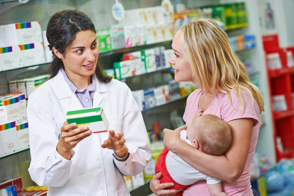 Pharmacist giving prescription to mother and baby